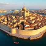 Zakaj je Valletta najlepše mesto na Malti? Valletta, prestolnica Malte, se bohoti na polotoku med dvema pristaniščema in očara z mogočnimi obzidji ter slikovito baročno arhitekturo.