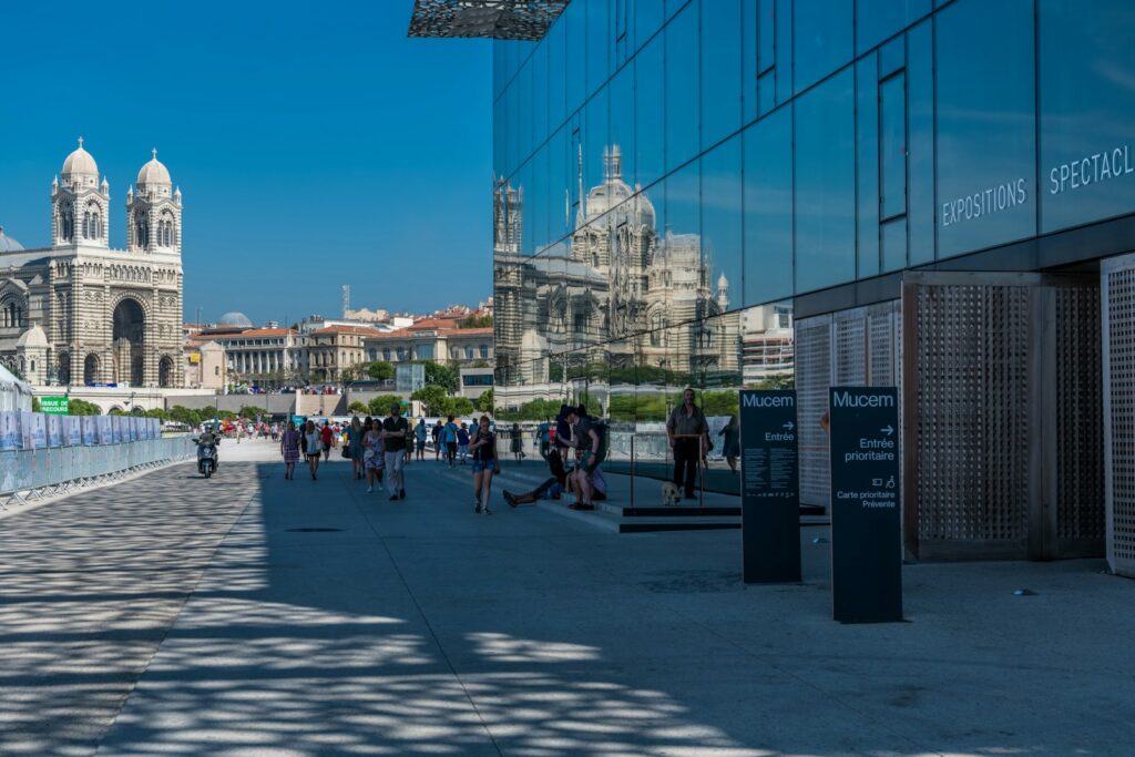 Moderna arhitektura MuCEM v Marseillu s pogledom na katedralo v odsevu steklene fasade.